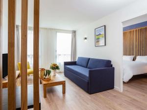 a living room with a blue couch and a bed at Aparthotel Adagio Montpellier Centre Comedie in Montpellier +32 photos