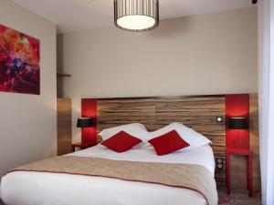 a bedroom with a large bed with two red pillows at Aparthotel Adagio Lyon Patio Confluence in Lyon +51 photos