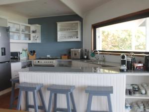 a kitchen with three stools and a counter in a kitchen at Ecos Oceano Ponta Malongane in Ponta Malongane +12 photos