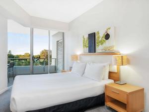 a bedroom with a large bed and a balcony at The Sebel Maroochydore in Maroochydore