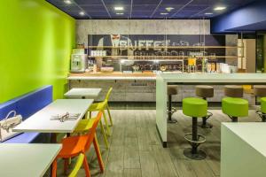 a restaurant with colorful chairs and tables and a counter at ibis budget Hamburg City in Hamburg