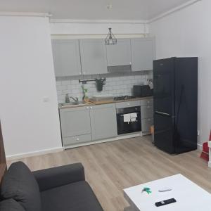 a kitchen with white cabinets and a black refrigerator at Trio Caracatita in Otopeni +17 photos