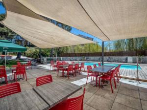 Un patio con mesas y sillas y una piscina. en Mercure Aix-en-Provence La Duranne Gare TGV, en Aix-en-Provence