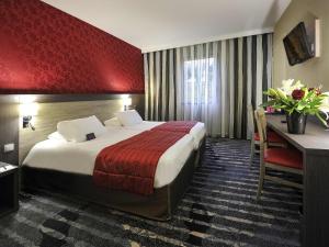 a hotel room with a large bed and a desk at Mercure Rouen Val de Reuil in Val de Reuil