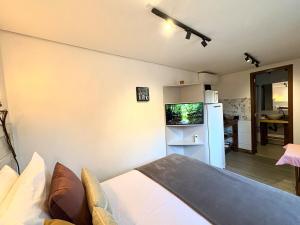 a room with a bed and a white refrigerator at Tiny House Passaúna - Climatizado, parque e deck in Curitiba