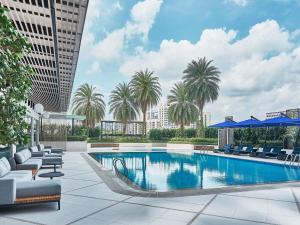 シンガポールにあるNovotel Singapore on Kitchenerの椅子とヤシの木が置かれた建物の屋上のプール
