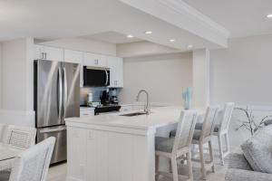 a kitchen with a stainless steel refrigerator and white cabinets at Sundial K402 - Executive Beach View Two Bedroom Penthouse at Sundial Sanibel in Sanibel