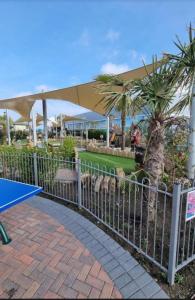 a fence with a ping pong table and palm trees at Fabulous seaside caravan getway at Cayton Bay in Scarborough