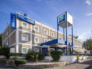 un hotel con señales azules en el lateral de un edificio en ibis budget Antibes Sophia Antipolis, en Vallauris