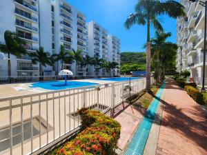 a resort with a swimming pool and palm trees and buildings at Hermoso apartamento fresco en medio de la naturaleza in Girardot