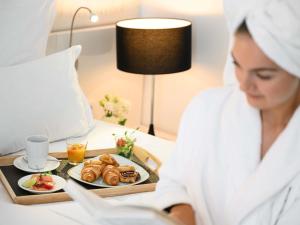una mujer en una habitación de hotel con una bandeja de comida en Nemzeti Hotel Budapest - MGallery Collection, en Budapest