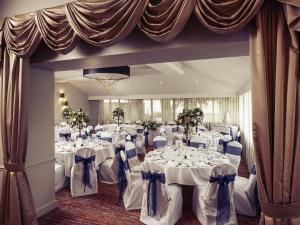a banquet room with white tables and blue chairs at Mercure Bristol North The Grange Hotel in Bristol