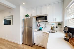 Una cocina con gabinetes blancos y un refrigerador de acero inoxidable. en Fair Weather, en Newport Heights 12 fotos más