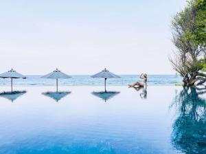un grupo de personas en una piscina con sombrillas en V Villas Hua Hin - MGallery Collection, en Hua Hin