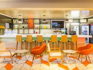 ポルト・アレグレにあるNovotel Porto Alegre Airportの椅子とカウンターのあるバーがあるレストラン