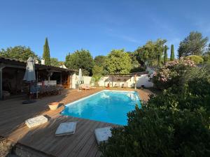 une piscine avec une terrasse en bois et une maison dans l'établissement La Belle Rivière, à Salernes