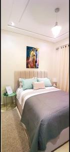 a bedroom with a bed with a painting on the wall at Modern Apartment with Balcony in Kenitra