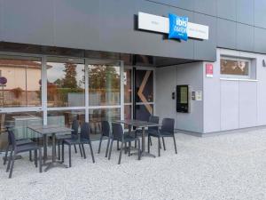 a group of tables and chairs in front of a building at Ibis Budget Mont De Marsan in Mont-de-Marsan