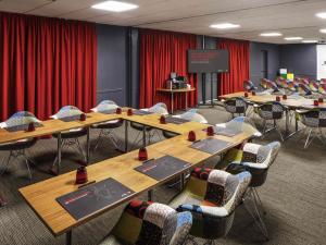 a conference room with tables and chairs and a screen at Ibis London Luton Airport in Luton