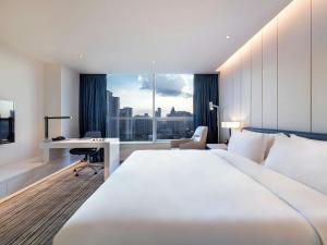 a hotel room with a large bed and a desk at Grand Mercure Shanghai Century Park- Free Shuttle Bus to SNIEC in Shanghai