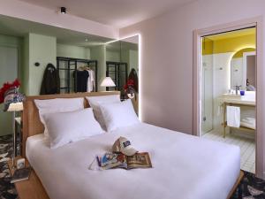 a bedroom with a large white bed with a mirror at Mama Shelter Roma in Rome