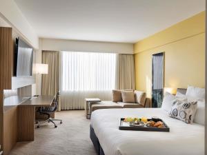 a hotel room with a bed with a tray of food on it at Novotel Auckland Ellerslie in Auckland