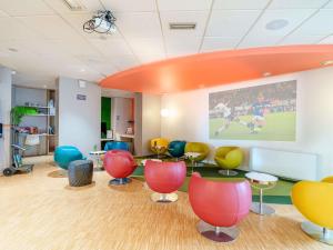 an office with colorful chairs and a large painting on the wall at ibis Styles Strasbourg Stade de la Meinau in Strasbourg