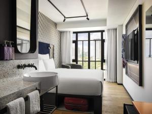 a hotel room with a bed and a sink at TRIBE Phnom Penh Post Office in Phnom Penh