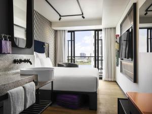 a hotel room with a white bed and a sink at TRIBE Phnom Penh Post Office in Phnom Penh +135 photos