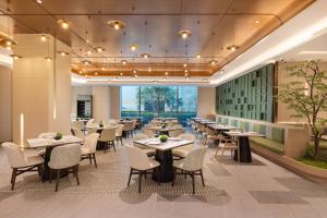 a dining room with tables and chairs and windows at Holiday Inn Shanghai Minhang Center by IHG in Shanghai
