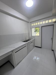 cocina blanca con fregadero y puerta en Diva house, en Chiang Mai