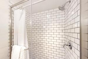 a bathroom with a shower with white tiled walls at Boothbay Cottage in Boothbay Harbor +23 photos
