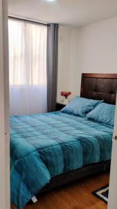 a bedroom with a bed with a blue comforter and a window at Departamento 4 personas, sector Peñuelas in La Serena +11 photos