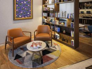 biblioteca con 2 sillas, mesa y estanterías en ibis Jaipur City Centre - An Accor Brand, en Jaipur