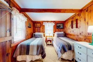 two beds in a room with wooden walls at Big Cottage in Flaggs Trailer Park