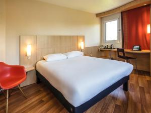 a large bed in a room with a red chair at Ibis Château-Thierry in Essômes-sur-Marne