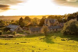 eine Gruppe von Häusern auf einem Feld mit Sonnenuntergang in der Unterkunft Luxury Manor House in the Oxfordshire Cotswolds in Garforth