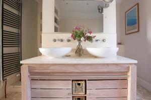 ein Badezimmer mit zwei Waschbecken auf einer Theke mit Blumen in der Unterkunft Luxury Manor House in the Oxfordshire Cotswolds in Garforth