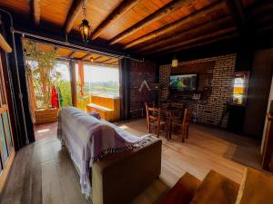 a living room with a couch and a television and a table at Bangalô house - Praia do Rosa SC in Praia do Rosa