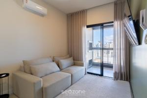 a living room with a couch and a large window at Sua estadia completa a 800m da Praia em Floripa - CLG in Florianópolis