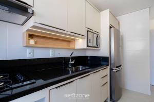 a white kitchen with a sink and a refrigerator at Sua estadia completa a 800m da Praia em Floripa - CLG in Florianópolis +11 photos