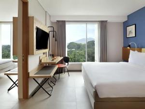 a hotel room with a bed and a desk with a computer at ibis Styles Bogor Pajajaran in Bogor