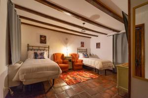 Un dormitorio con dos camas y un sofá y una silla. en Hospedium Hostería Rural Isabel La Católica, en Aranda de Duero