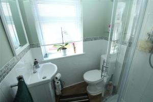 a bathroom with a toilet and a sink and a window at Spacious 4-Bed House in Welling - Free parking in Welling