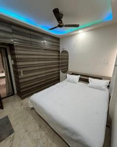 een slaapkamer met een wit bed met een plafondventilator bij 2BHK Galaxy Height Shree Nagar Nagpur in Nagpur
