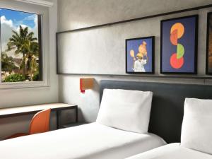 a hotel room with two beds and a window at Ibis Styles Abidjan Plateau in Abidjan