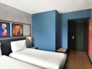 a room with two beds and a blue wall at Ibis Styles Abidjan Plateau in Abidjan +80 photos