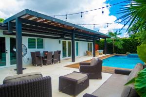 een terras met stoelen en een zwembad bij Greenview Villa/Luxury Heated Pool Home Golf View in Kendale Lakes