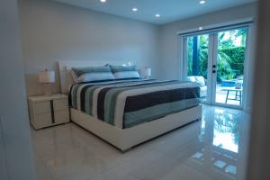 een witte slaapkamer met een bed en een glazen schuifdeur bij Greenview Villa/Luxury Heated Pool Home Golf View in Kendale Lakes +100 foto's