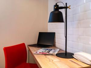 biurko z laptopem, lampą i telefonem w obiekcie Greet Boulogne Billancourt Paris w mieście Boulogne-Billancourt